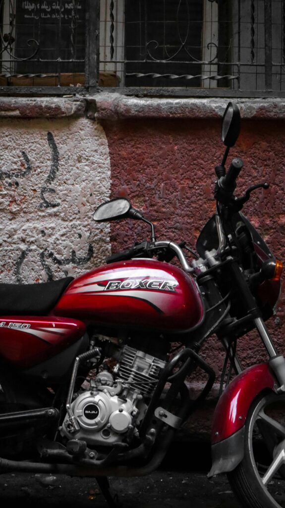 Classic red Boxer motorcycle parked against a textured wall with graffiti.